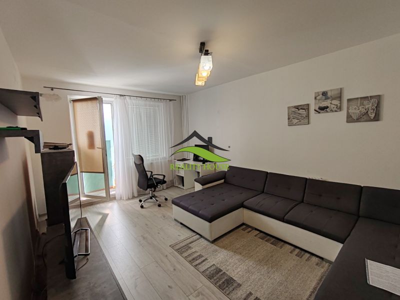 Living room in a 3-room apartment with a wooden decor floor, workspace, and a sofa.