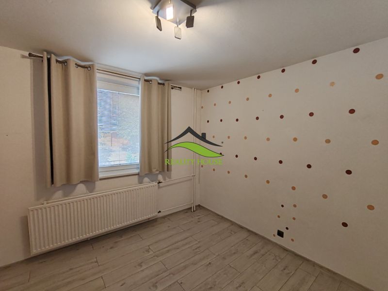 A room in a 3-room apartment with a wooden decor floor and dotted wallpaper.