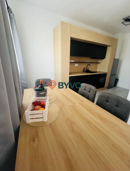 A kitchen in a 2-room apartment with a dining table and a wooden decor floor.