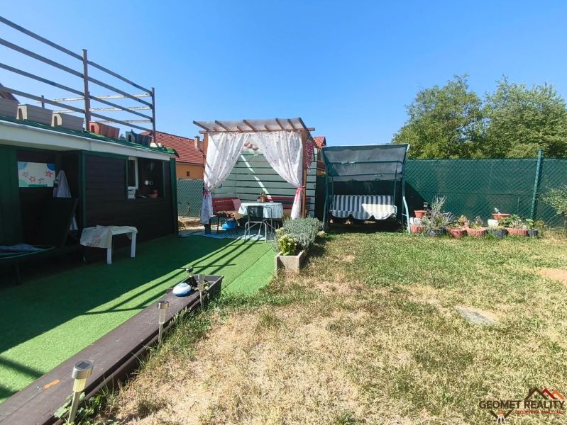The garden of a family house in Divín with a gazebo, a swing, and a green lawn.