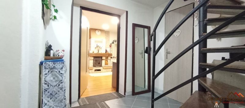 Interior of a family house with a staircase, wood-patterned flooring, and a fireplace.
