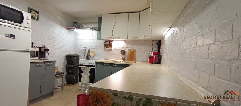A kitchen in a family house with white brick walls and kitchen appliances.