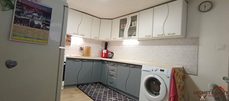 A kitchen in a family house with white and gray cabinets, a floor with a wooden decor.