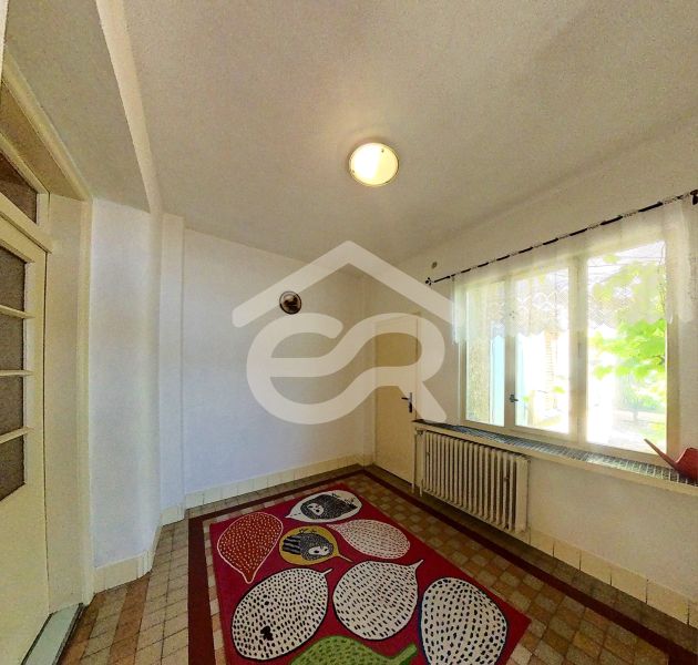 In the family house, there is a room with a colorful carpet, a window, and a wall with a radiator.