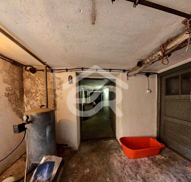 The basement of a family house with a tank and an orange plastic container on the floor.