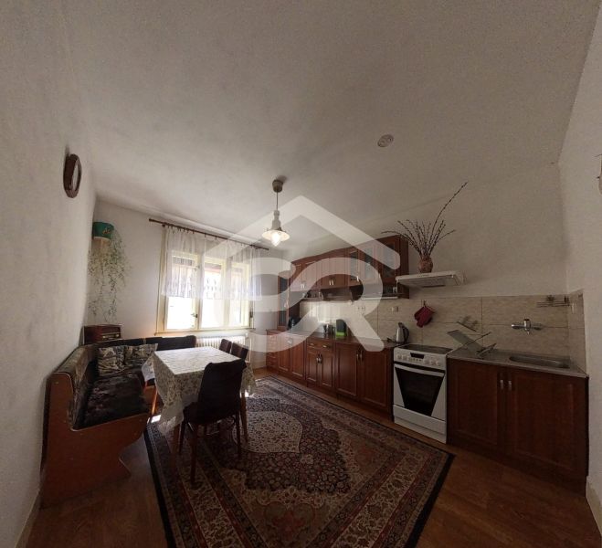 A kitchen with built-in cabinets, a gas stove, and a wooden-patterned floor in a family house.