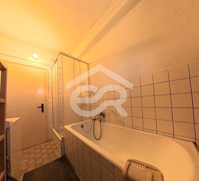 Bathroom with a bathtub, shower, and tiles in a family house.