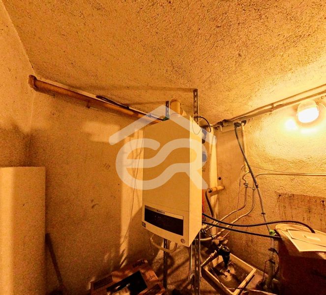 Bathroom in a family house with fixtures and pipes, illuminated by a light bulb.