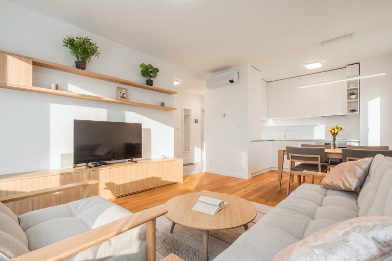 Living room in a two-room apartment with a wooden decor floor and light furniture.