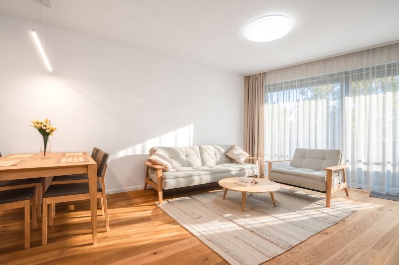 A bright living room with wood-patterned flooring, a sofa, and a dining table.