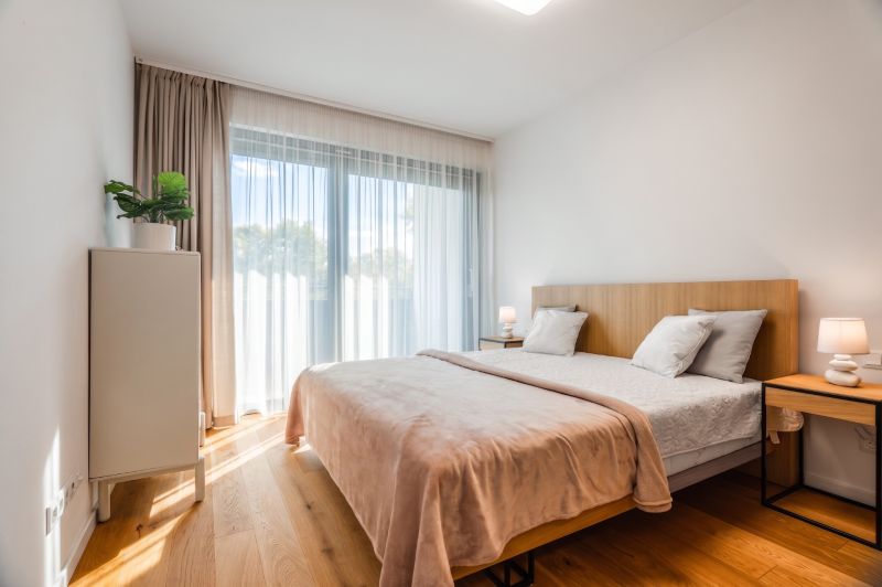 Bedroom in a two-room apartment with a bed, curtains, nightstands, and a floor with a wood decor.