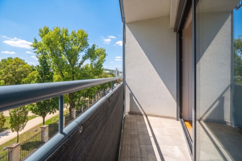 Balcony of a 2-room apartment with a view of greenery and blue sky.