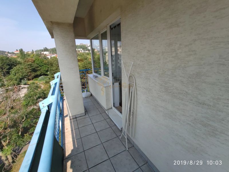 The balcony of a 2-room apartment with blue railings and a view of greenery in Bratislava.