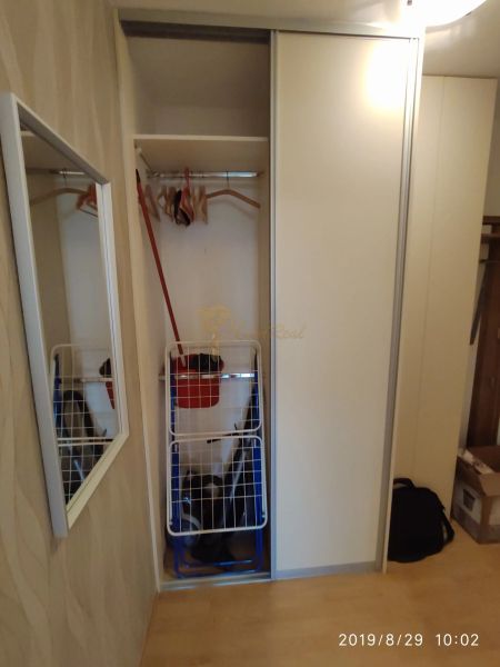 Built-in wardrobe with sliding doors, hangers, and a mirror in a 2-room apartment.