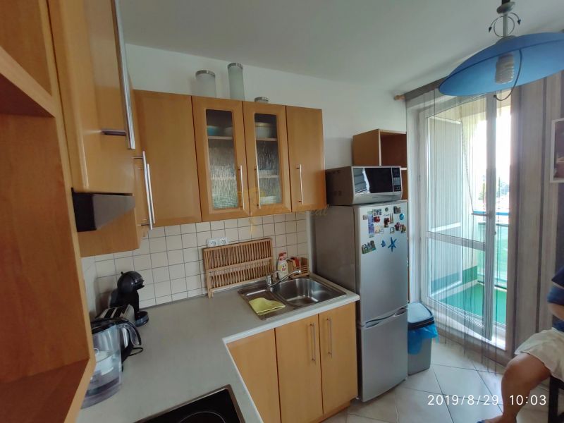 A kitchen with wooden cabinets, a microwave, and a refrigerator in a two-room apartment.