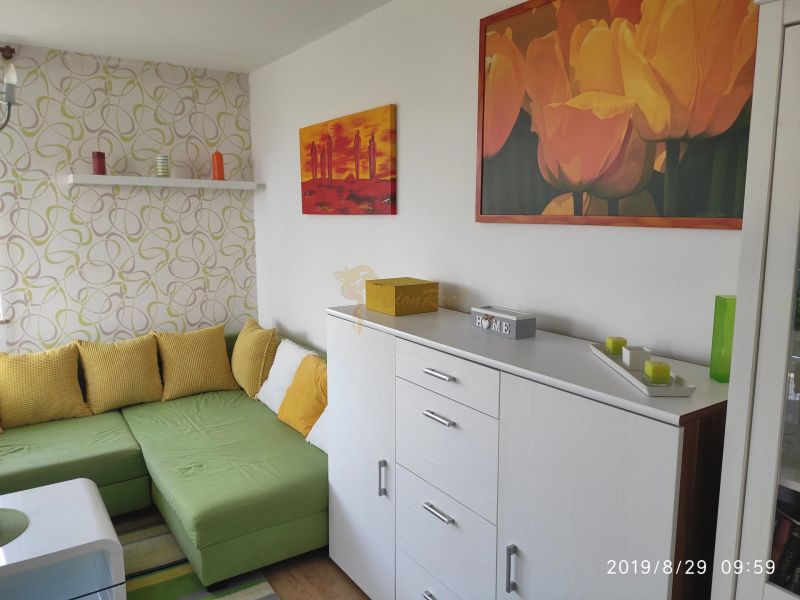 Living room with a sofa, wooden decor flooring, decorative paintings, and candles.