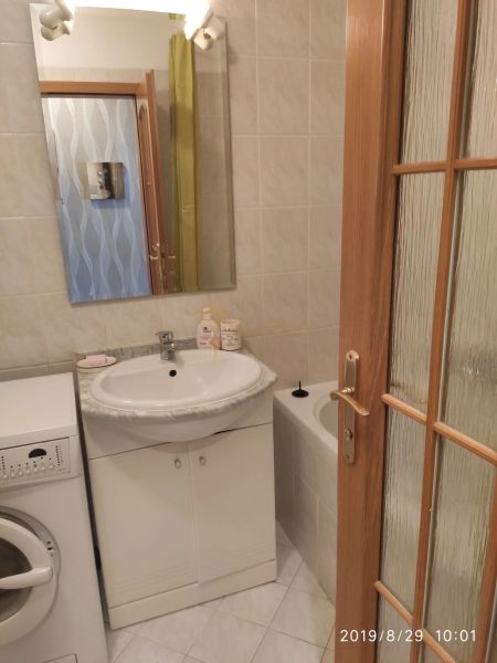 Bathroom with a sink, mirror, washing machine, and bathtub in a 2-room apartment.