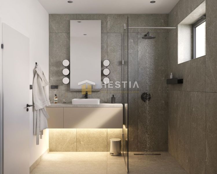 A bathroom in a family house with stone tiles, a shower, and a hanging mirror.