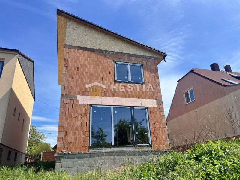 A family house in Cerová with an unfinished brick facade and large glass doors.