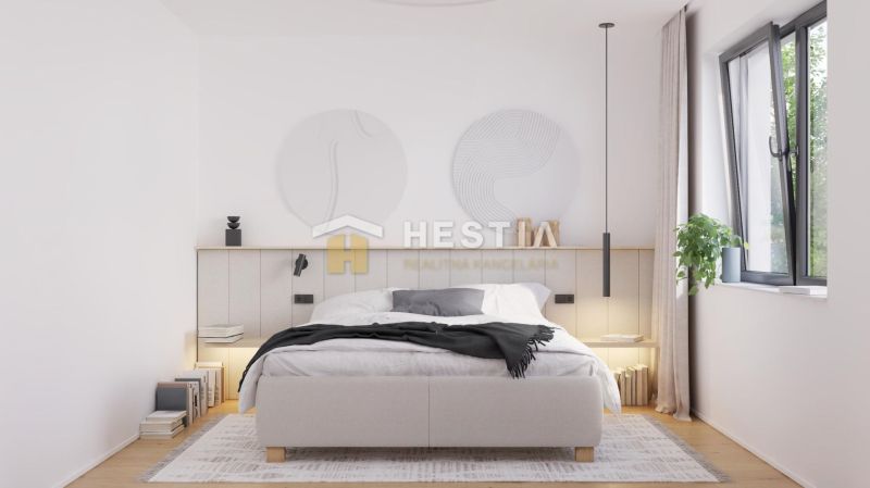 A bedroom in a family house with a bed, a plant, and a wooden decor floor.