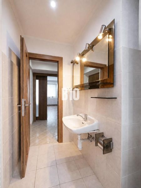 Bathroom with a sink in a three-room apartment with a wooden decor floor.