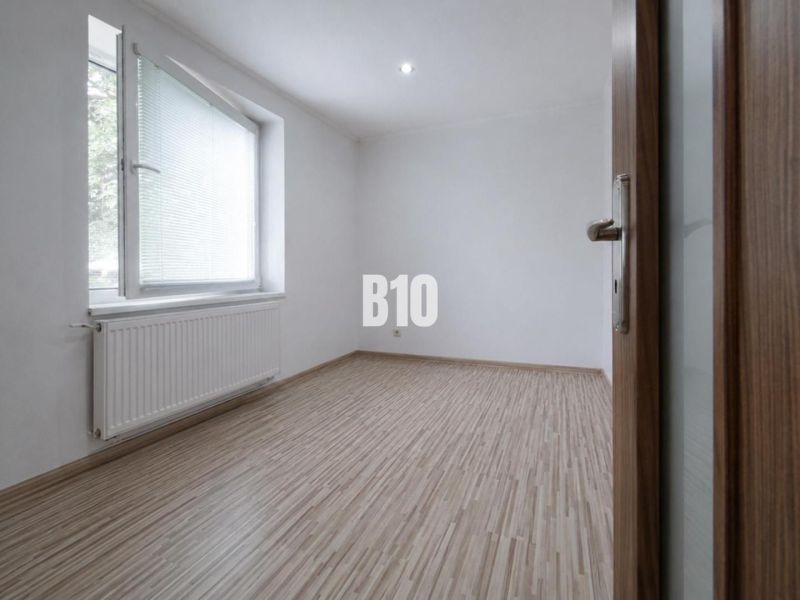 An empty room with a wood-patterned floor in a three-room apartment.