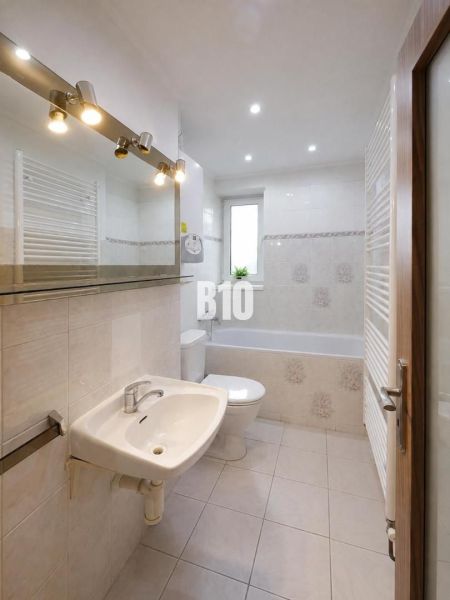A bathroom with a bathtub, sink, and window in a 3-room apartment.