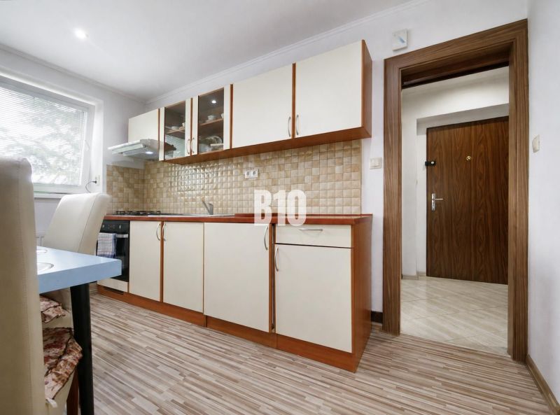 A kitchen with a wooden decor floor in a 3-room apartment, equipped with light furniture.