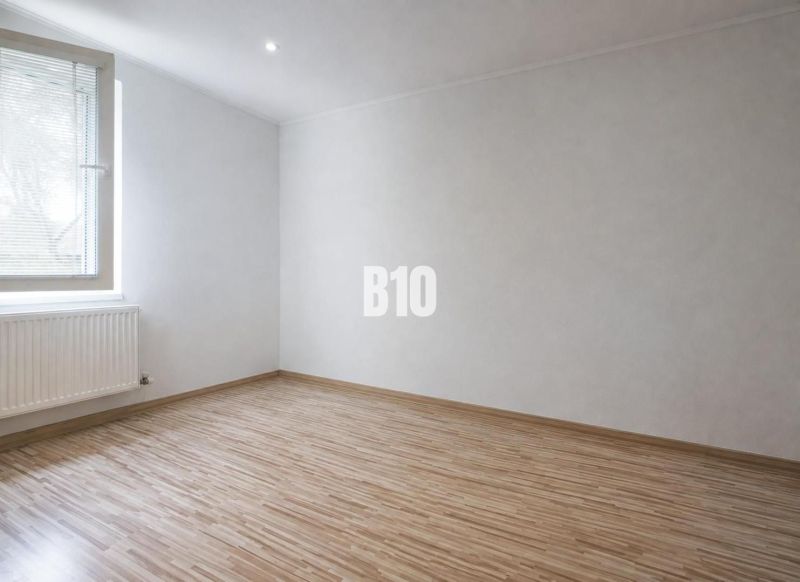 A room in a 3-room apartment with a wooden decor floor and white walls.