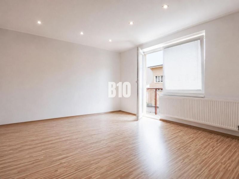 A spacious room in a 3-room apartment with a wooden decor floor and a large window.