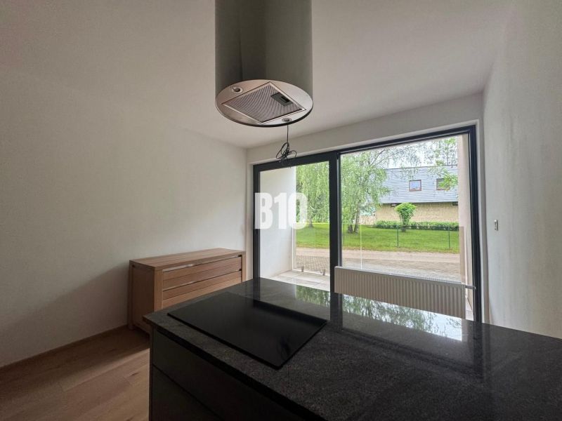 A kitchen in a 2-room apartment with a wooden decor floor and large windows.