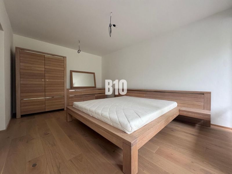 A bedroom in a two-room apartment with wooden furniture and a floor with a wood decor.
