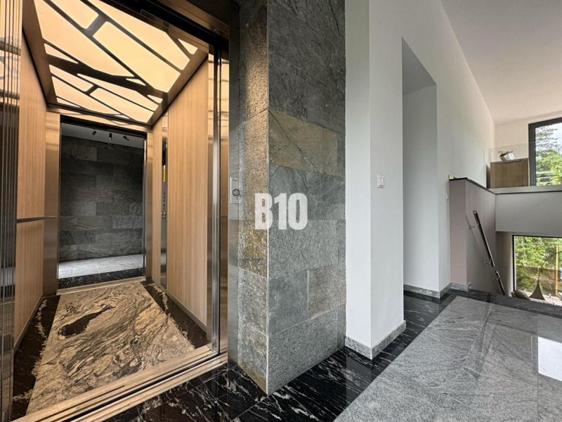 A hallway with a stylish elevator in a 2-room apartment, with stone walls and flooring.