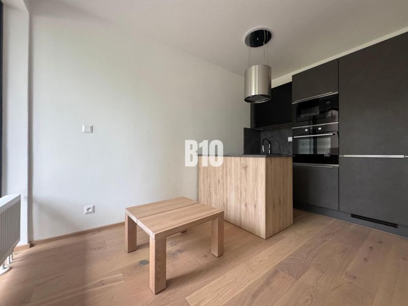 A kitchen corner with dark cabinets and a wooden decor floor in a 2-room apartment.