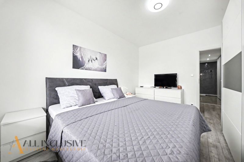 Bedroom in a 3-room apartment with a double bed, television, and floor with wooden decor.