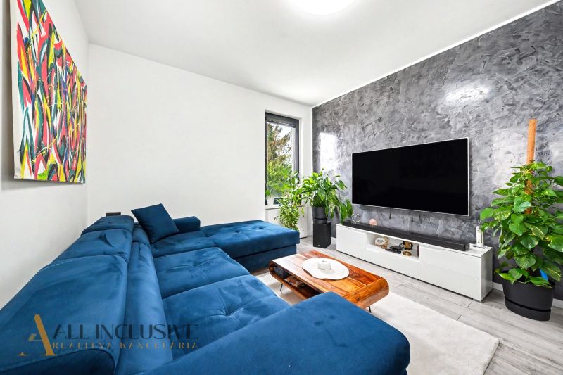 Living room in a 3-room apartment with a sofa bed, TV, and plants.
