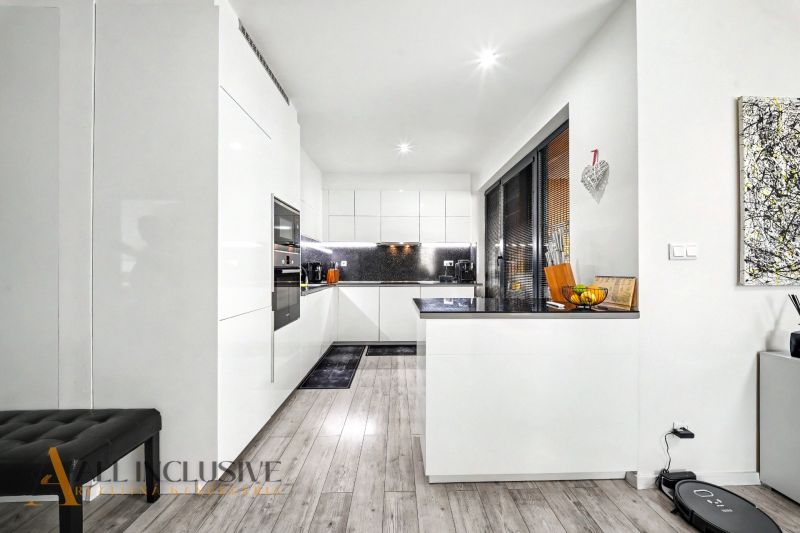 A kitchen in a 3-room apartment with white furniture and a wooden decor floor.