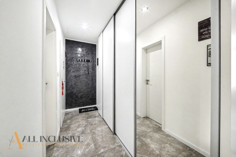 A hallway with white walls, a sliding wardrobe, and a stone floor in a 3-room apartment.