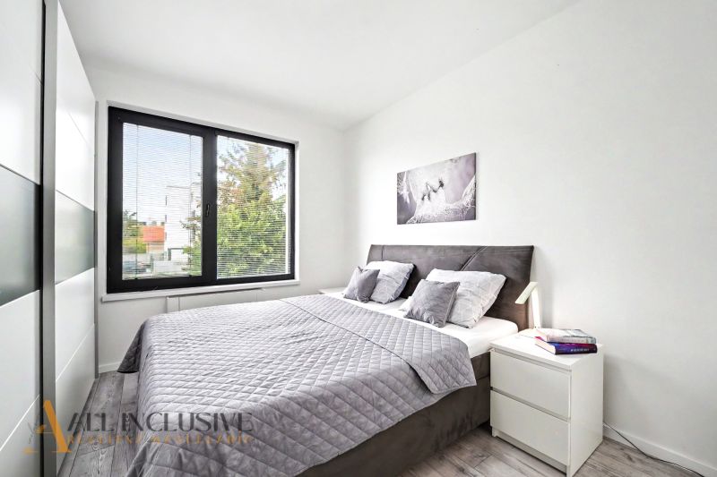 Bedroom in a 3-room apartment with a wood-patterned floor, a large bed, and a painting on the wall.