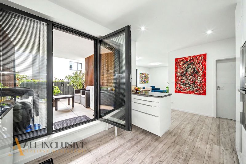Interior of a 3-room apartment with a balcony, wooden decor flooring, and colorful art.