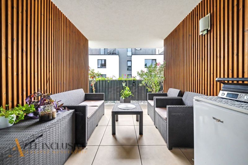 Furnished terrace of a 3-room apartment with rattan furniture and floral decorations.