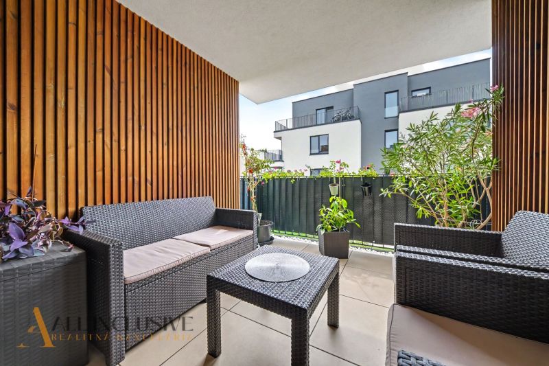 A balcony of a 3-room apartment with rattan furniture and plants.