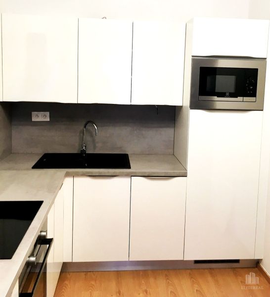 White kitchen with a microwave and built-in sink, 2-room apartment, floor with wood decor.