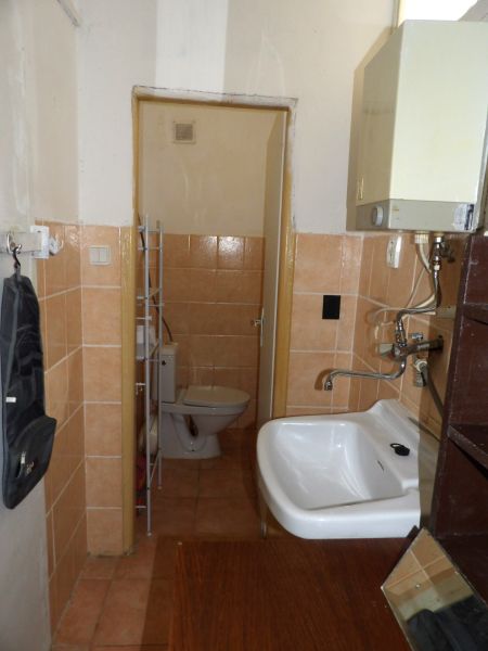 Bathroom of a 2-room apartment with a toilet and a sink in a simple style.
