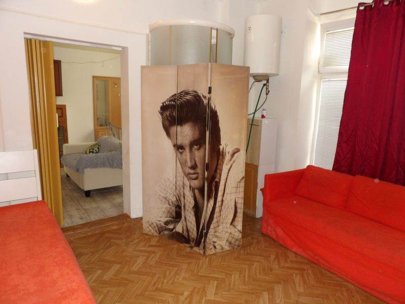 A red sofa and a screen with a black and white photo in a 2-room apartment with colorful curtains.