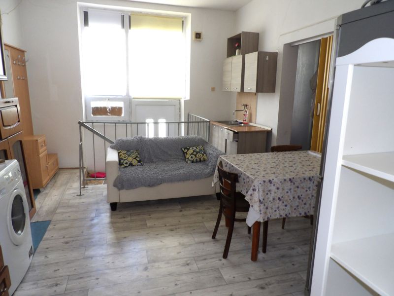 Living room in a two-room apartment with a wooden decor floor and simple furnishings.