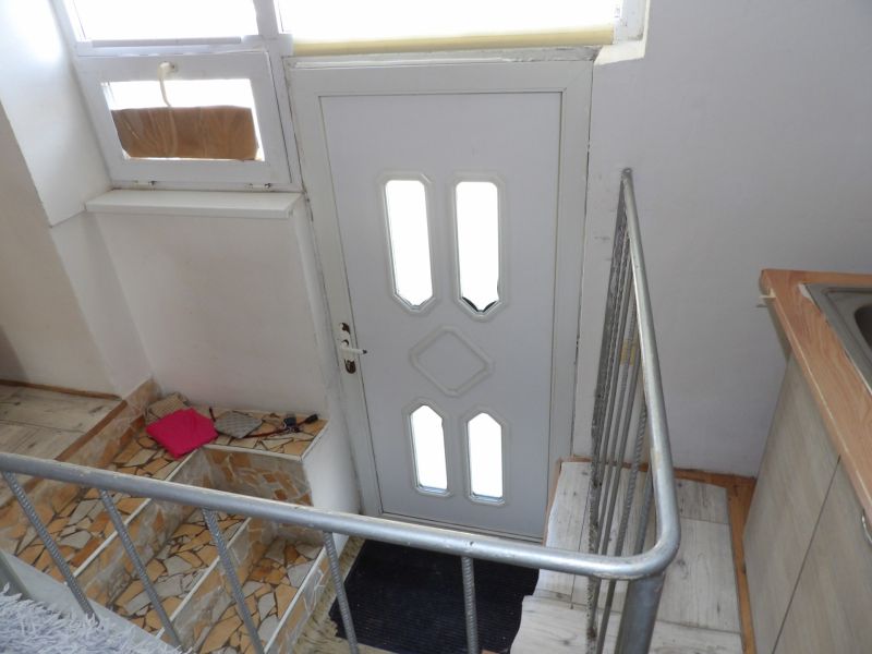 Stairs and entrance door in a 2-room apartment with a railing and mosaic tiles.