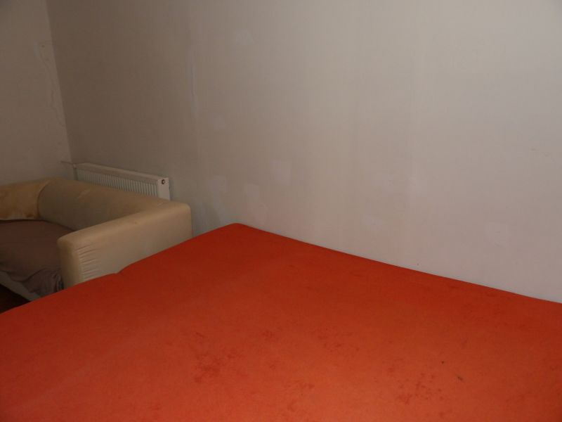 A room with an orange bed and a beige armchair in a 2-room apartment.