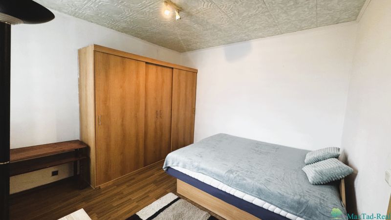 Bedroom in a 4-room apartment with a bed, wardrobe, and wooden decor flooring.