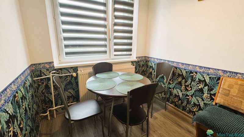 Dining area in a 4-room apartment with floral wallpaper and a table for four.